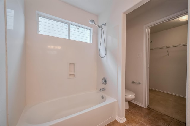 full bathroom featuring tile patterned flooring, a walk in closet, baseboards, toilet, and shower / bathing tub combination