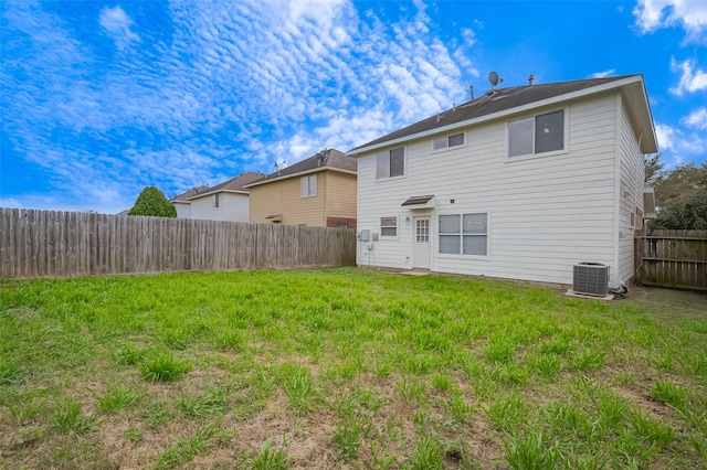 rear view of house featuring central air condition unit, a yard, and a fenced backyard