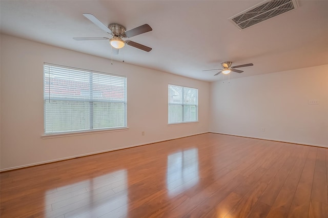 unfurnished room featuring wood finished floors, visible vents, and ceiling fan