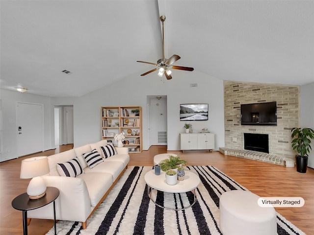 living room with visible vents, wood finished floors, a fireplace, and vaulted ceiling