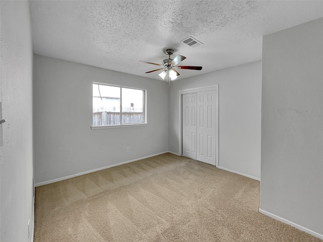 unfurnished bedroom featuring baseboards, visible vents, carpet floors, a closet, and a textured ceiling