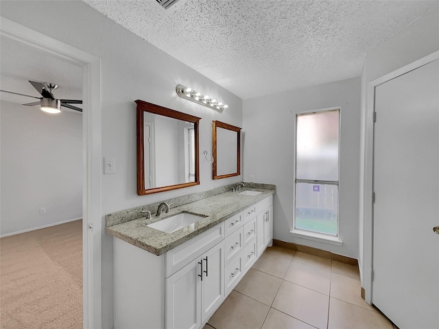 bathroom featuring a sink, a ceiling fan, a textured ceiling, and double vanity