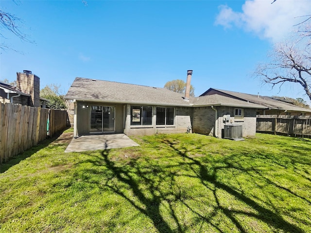 rear view of house featuring central air condition unit, a lawn, a fenced backyard, brick siding, and a patio area