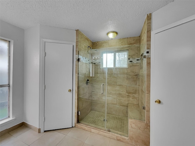 bathroom with tile patterned floors, baseboards, a textured ceiling, and a shower stall