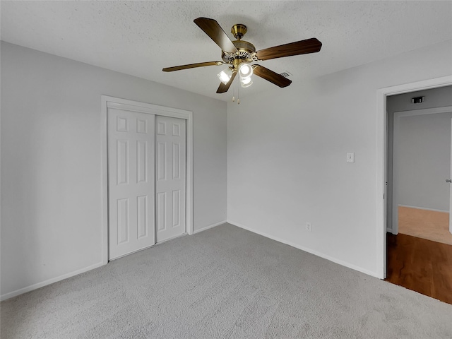 unfurnished bedroom featuring baseboards, carpet floors, ceiling fan, a closet, and a textured ceiling