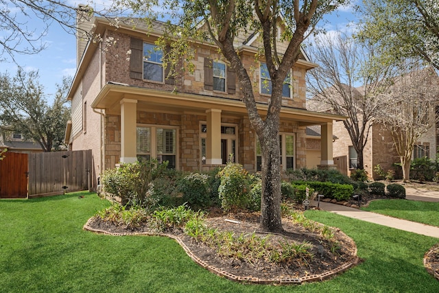 view of front of property featuring stone siding, a front lawn, and fence