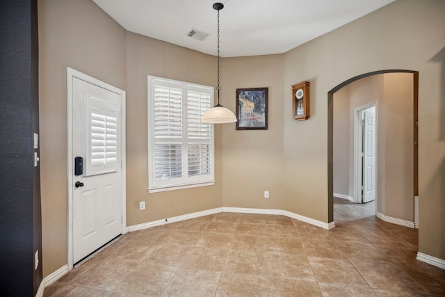 entrance foyer with light tile patterned floors, visible vents, arched walkways, and baseboards