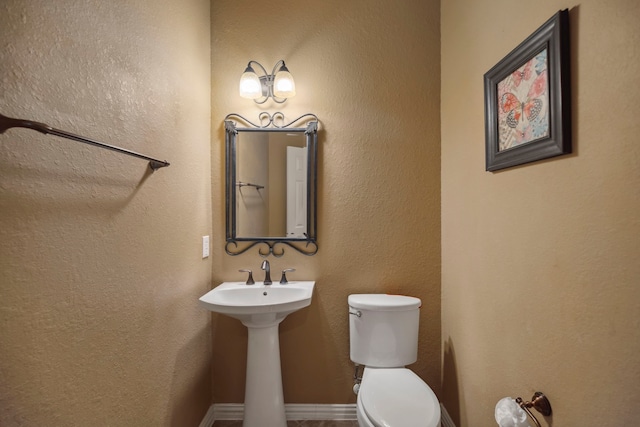 bathroom with toilet and a textured wall