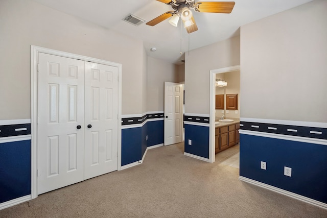 interior space featuring visible vents, light countertops, light carpet, a ceiling fan, and a sink