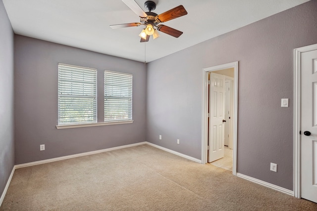 empty room with a ceiling fan, light colored carpet, and baseboards