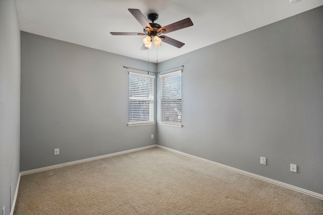 carpeted empty room featuring baseboards and ceiling fan