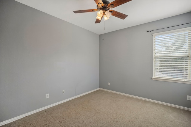 carpeted empty room with a ceiling fan and baseboards