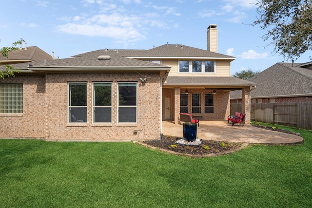 back of property with brick siding, a patio, fence, and a lawn