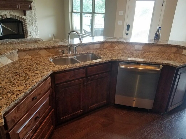 kitchen with light stone counters, dark wood-style flooring, a sink, stainless steel dishwasher, and a wealth of natural light