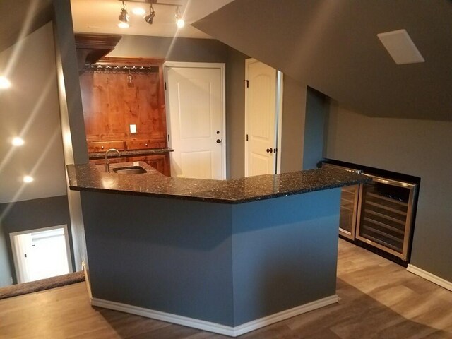 bar featuring wine cooler, light wood-style flooring, baseboards, and a sink