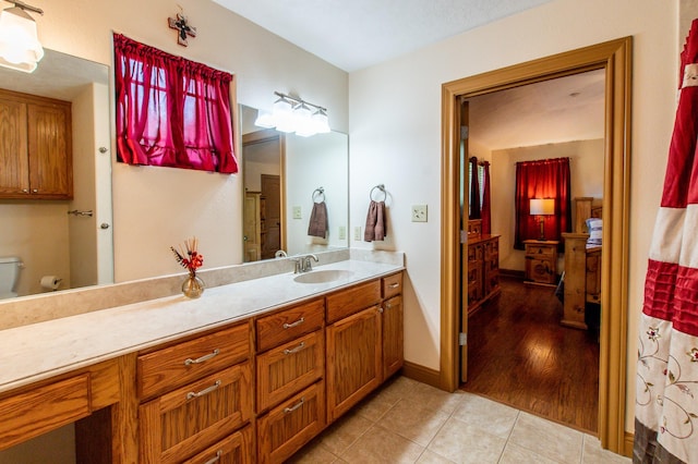 full bath featuring toilet, tile patterned flooring, baseboards, walk in shower, and vanity