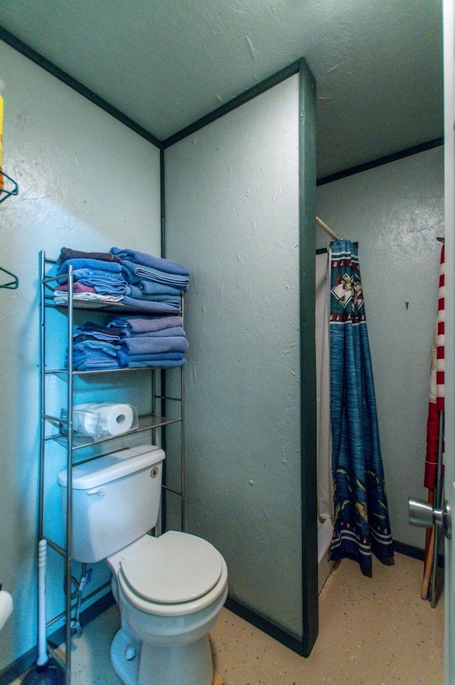 bathroom with a shower with curtain, toilet, concrete floors, and a textured wall