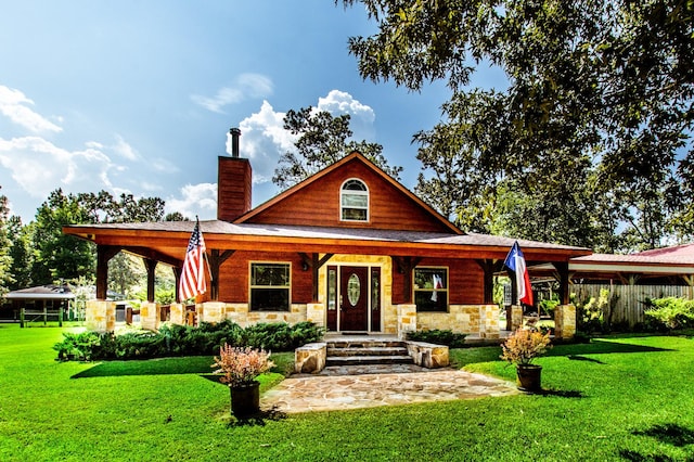 view of front of home featuring a front yard, a porch, stone siding, and a chimney