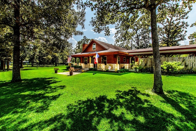 back of house with stone siding, a lawn, a chimney, and fence