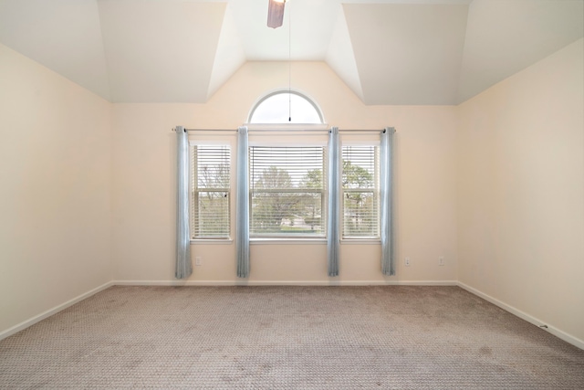 carpeted spare room featuring baseboards, lofted ceiling, and a ceiling fan