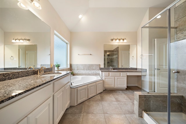 full bathroom with two vanities, a stall shower, a sink, vaulted ceiling, and a bath