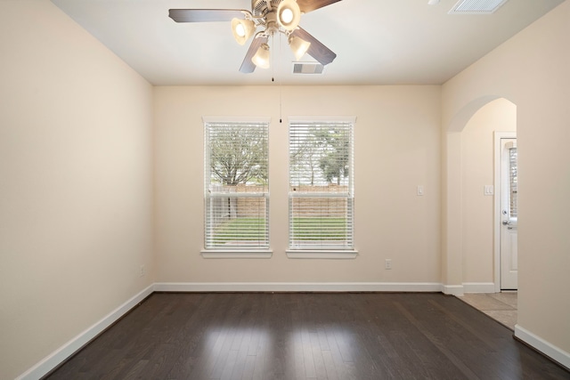 spare room featuring visible vents, ceiling fan, baseboards, wood finished floors, and arched walkways