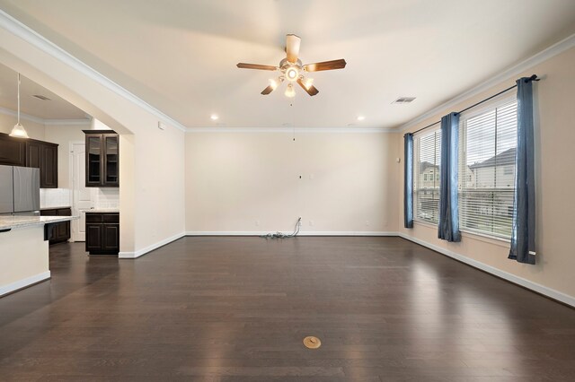 unfurnished living room with visible vents, dark wood-type flooring, ceiling fan, baseboards, and ornamental molding