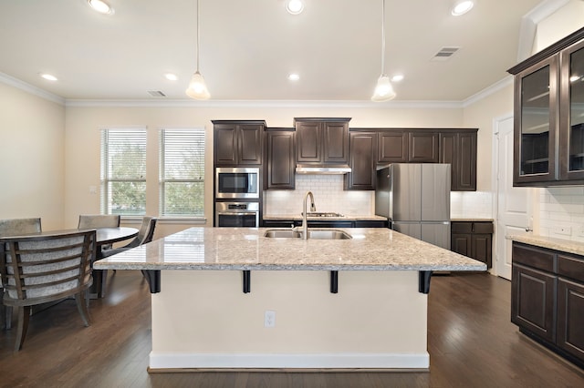 kitchen with dark brown cabinets, appliances with stainless steel finishes, a breakfast bar, and a sink