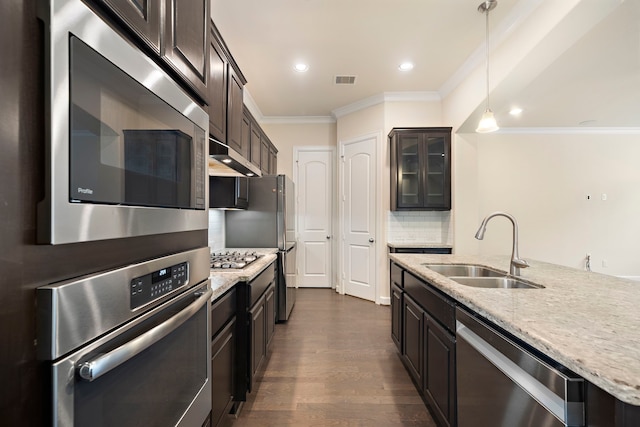 kitchen with ornamental molding, a sink, backsplash, dark wood finished floors, and appliances with stainless steel finishes