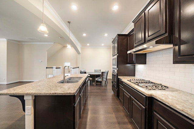 kitchen with a kitchen island with sink, a sink, under cabinet range hood, dark wood finished floors, and stainless steel appliances