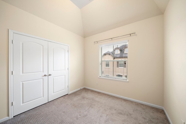 unfurnished bedroom featuring a closet, baseboards, carpet flooring, and vaulted ceiling