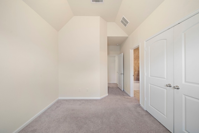 corridor with visible vents, baseboards, light colored carpet, and vaulted ceiling