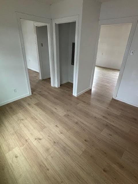 spare room with baseboards and wood finished floors