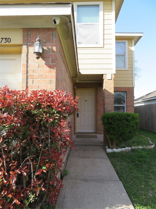 property entrance with brick siding and fence