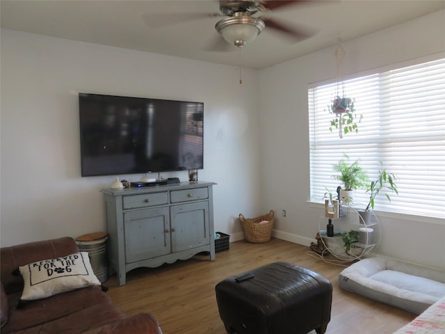 living area featuring plenty of natural light, light wood-style flooring, baseboards, and a ceiling fan