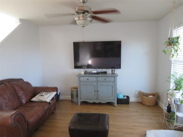 living area featuring ceiling fan, baseboards, and light wood-style flooring