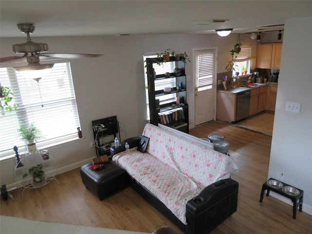 living area featuring plenty of natural light, a ceiling fan, baseboards, and light wood finished floors