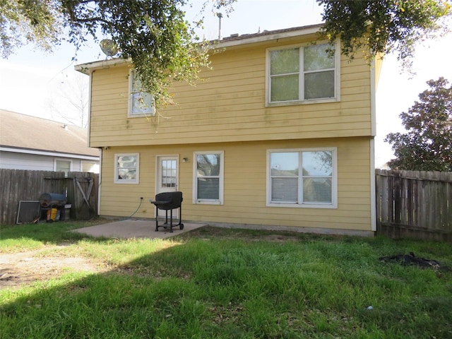 rear view of property with a fenced backyard, a lawn, and a patio