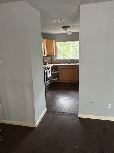 kitchen with electric range, visible vents, a sink, dark wood finished floors, and light countertops