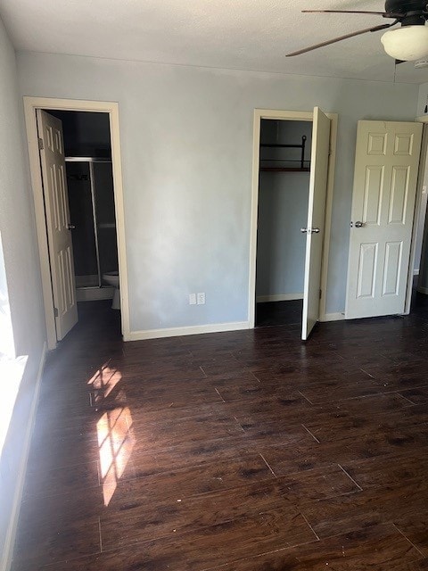 unfurnished bedroom with ensuite bath, a closet, baseboards, ceiling fan, and dark wood-style flooring