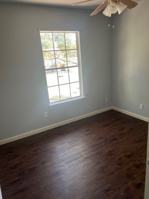 empty room with baseboards, dark wood-style floors, and a ceiling fan