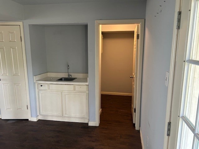 interior space with dark wood-style floors, baseboards, and a sink