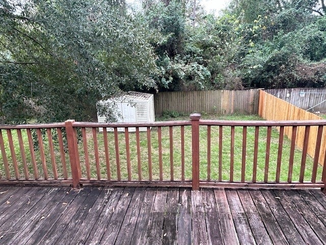 wooden terrace with an outdoor structure, a yard, a fenced backyard, and a shed