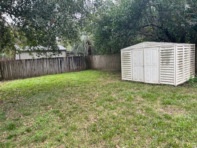 view of yard with a storage shed, an outbuilding, and a fenced backyard