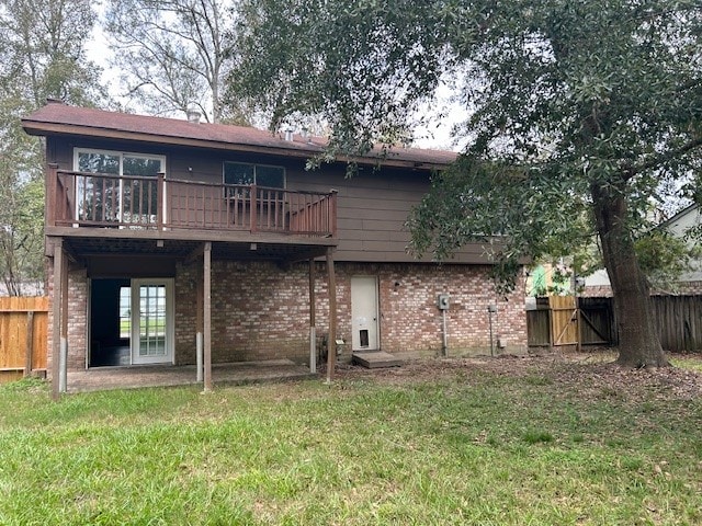 rear view of house with fence, brick siding, and a lawn