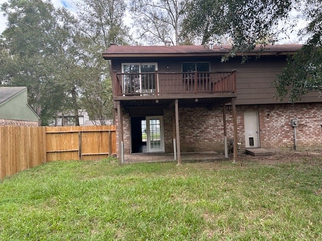 rear view of property featuring brick siding, a patio, a lawn, and fence