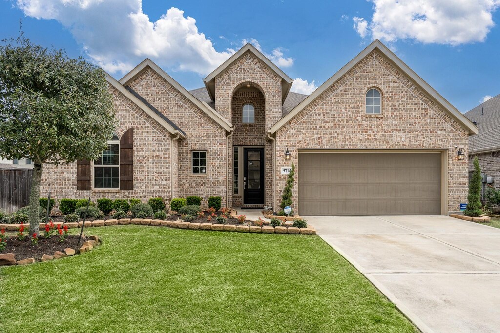 9714 Slumbering Willow Ln, Richmond, TX 77406 - view of front of home featuring brick siding, concrete driveway, a garage, and a front yard