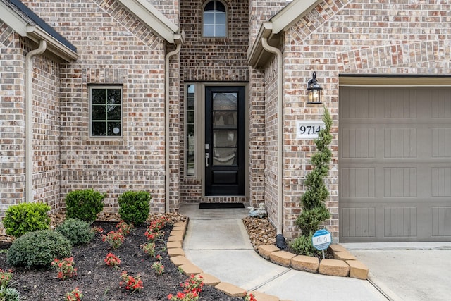 view of exterior entry featuring brick siding and an attached garage