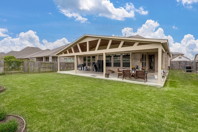 back of house featuring a patio, a lawn, a fenced backyard, and brick siding