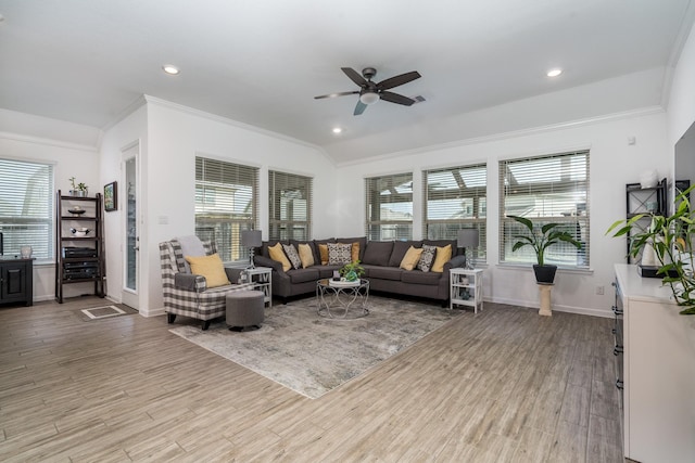 living area featuring a wealth of natural light, crown molding, light wood-type flooring, and baseboards